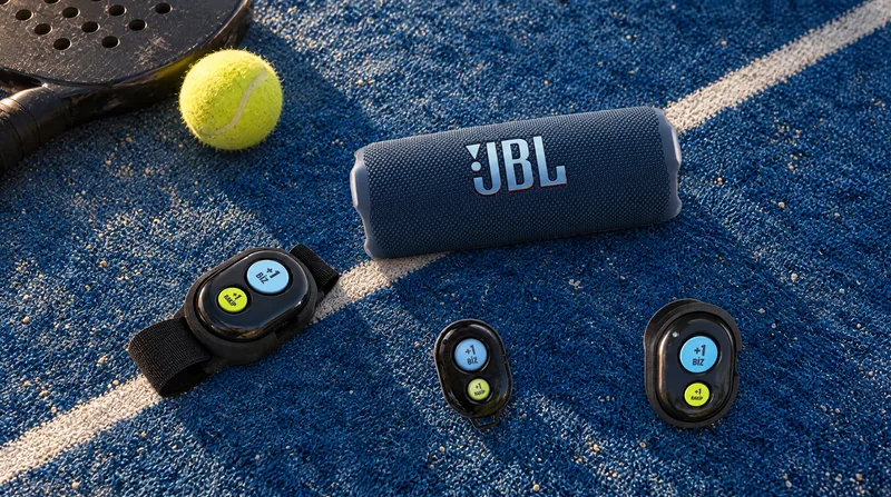 Enceinte JBL Flip 7 avec les télécommandes Bluetooth à bracelet, magnétique et porte-clés sur le sol du court